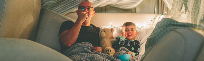 Father and Son Watching Movie with Popcorn in Heated Home